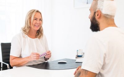 A staff member talks to their client after the hair transplant.